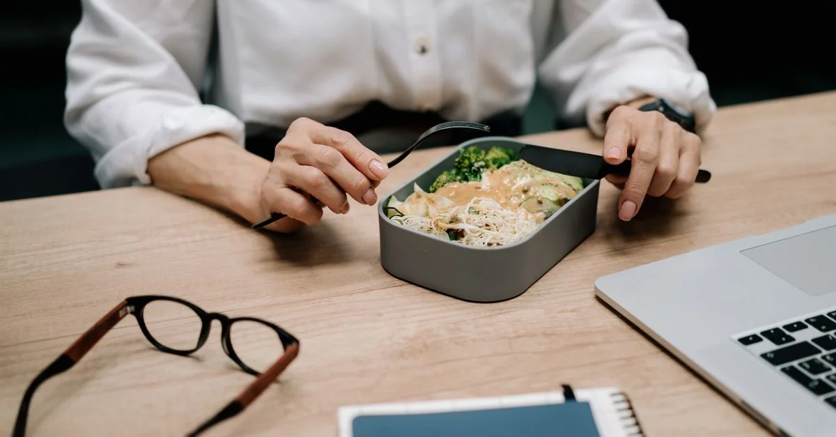 Un adulte dégustant un repas sain au bureau pendant la pause déjeuner.