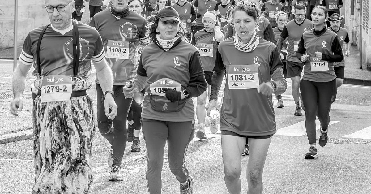 Un groupe diversifié de coureurs participe à un événement de course de rue animé.
