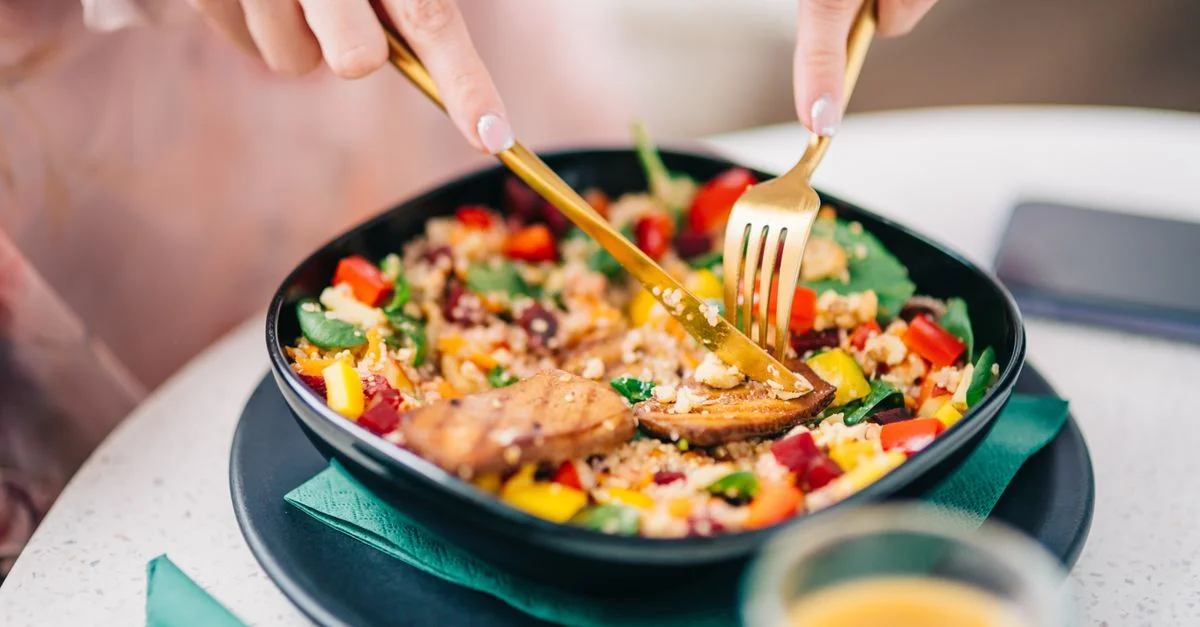 Salade de quinoa vibrante avec des légumes frais appréciée par un convive.