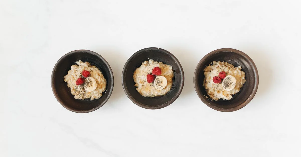 Délicieux bols de petit-déjeuner avec de la bouillie d'avoine, banane et framboises sur un fond blanc propre.