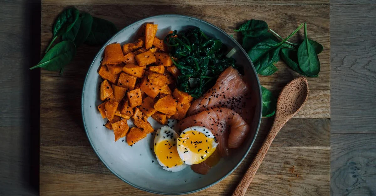 Repas délicieux et nutritif avec du saumon, de la patate douce et des œufs, parfait pour une alimentation saine.
