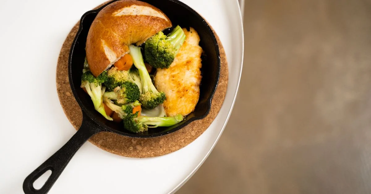 Gros plan d'une poêle à poulet avec brocoli, carottes et pain, parfait pour un repas sain.